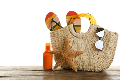 Photo of Stylish bag with beach accessories on wooden table