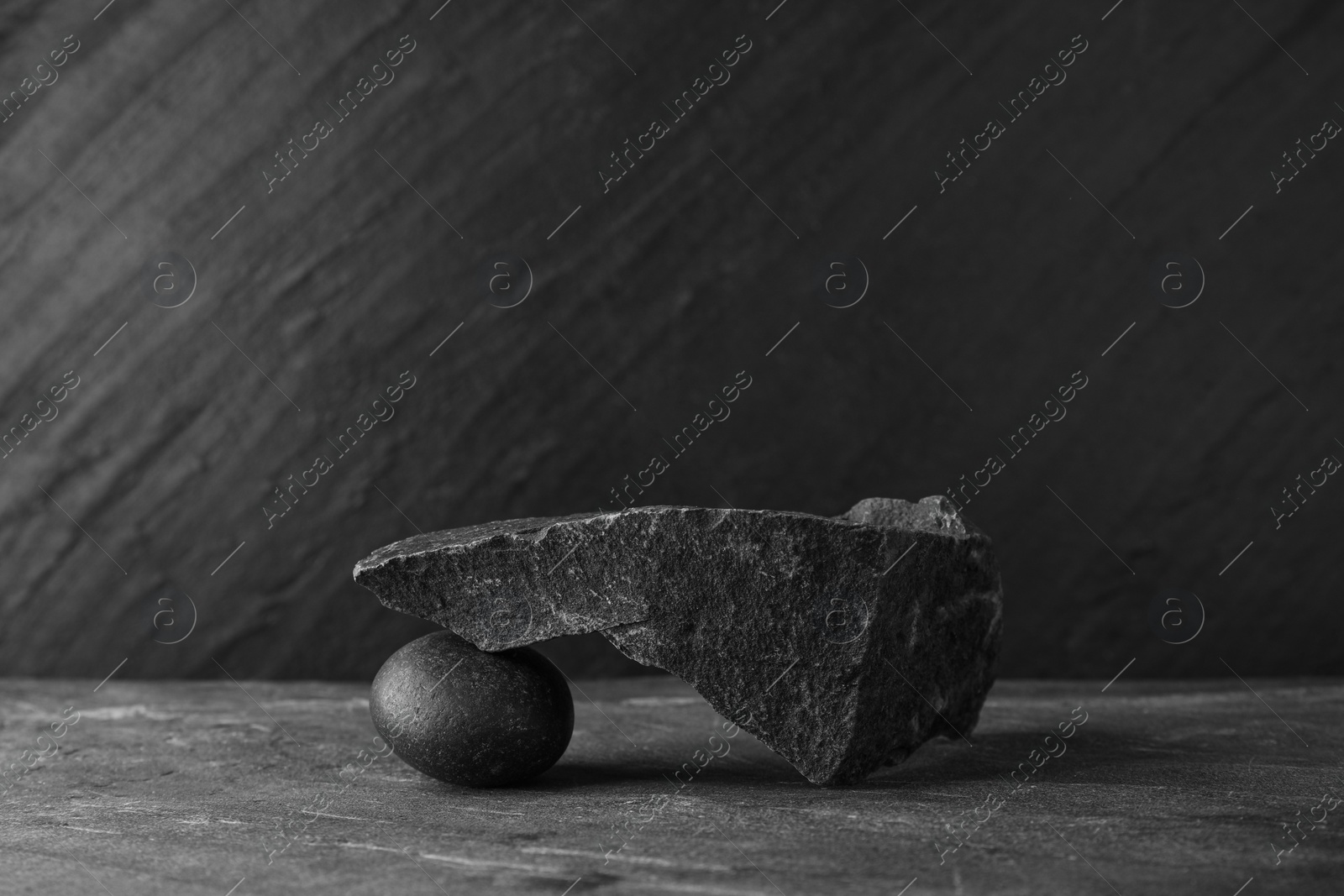 Photo of Presentation for product. Podium made of different stones on grey textured background. Space for text