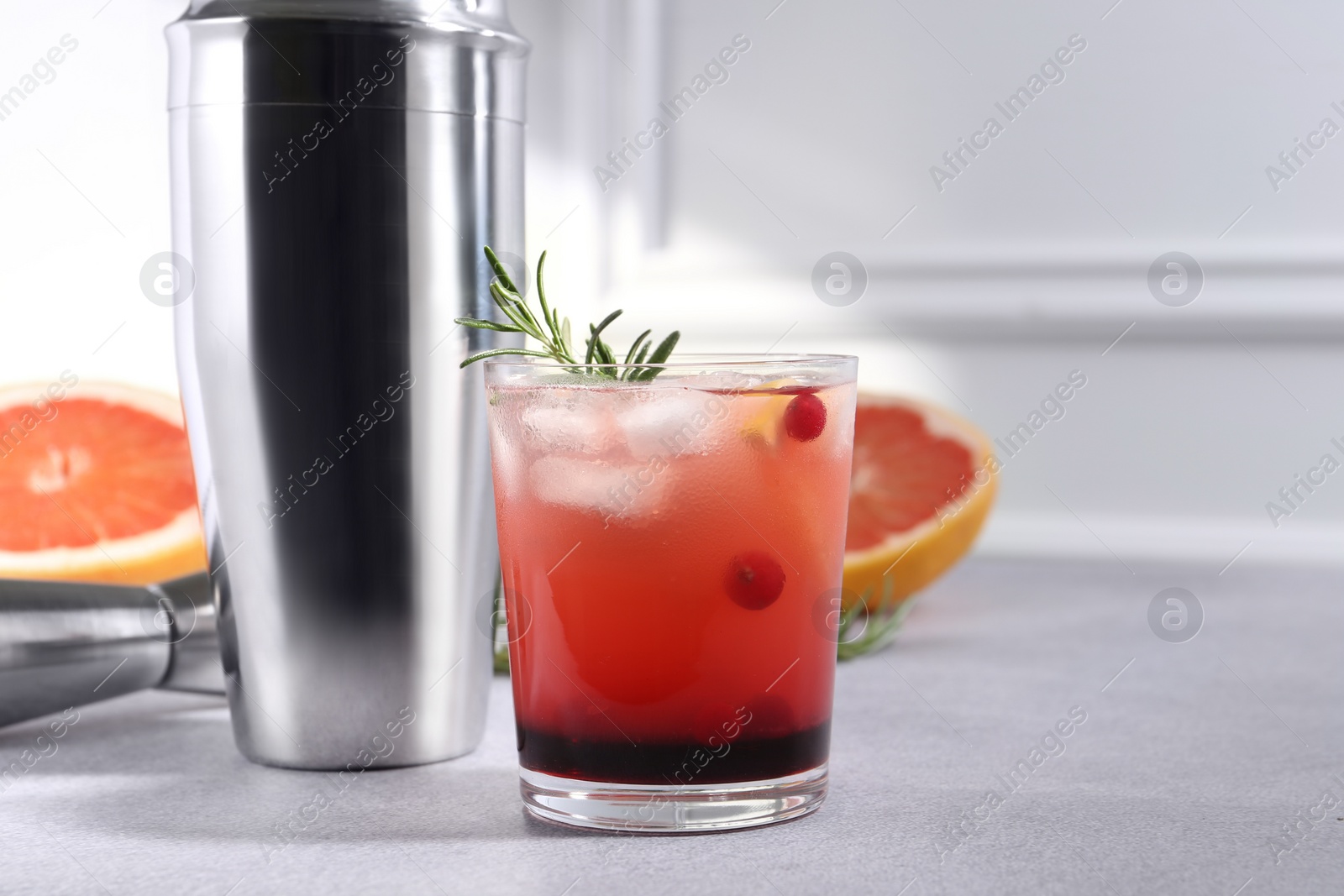 Photo of Delicious cocktail, grapefruit and bartender equipment on light grey table, space for text