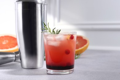 Photo of Delicious cocktail, grapefruit and bartender equipment on light grey table, space for text