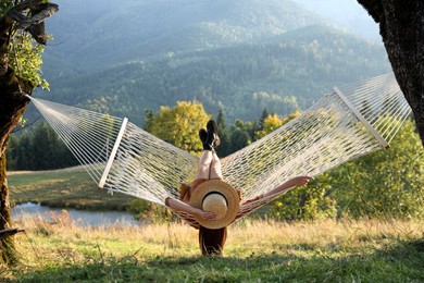 Photo of Young woman resting in hammock outdoors at sunset