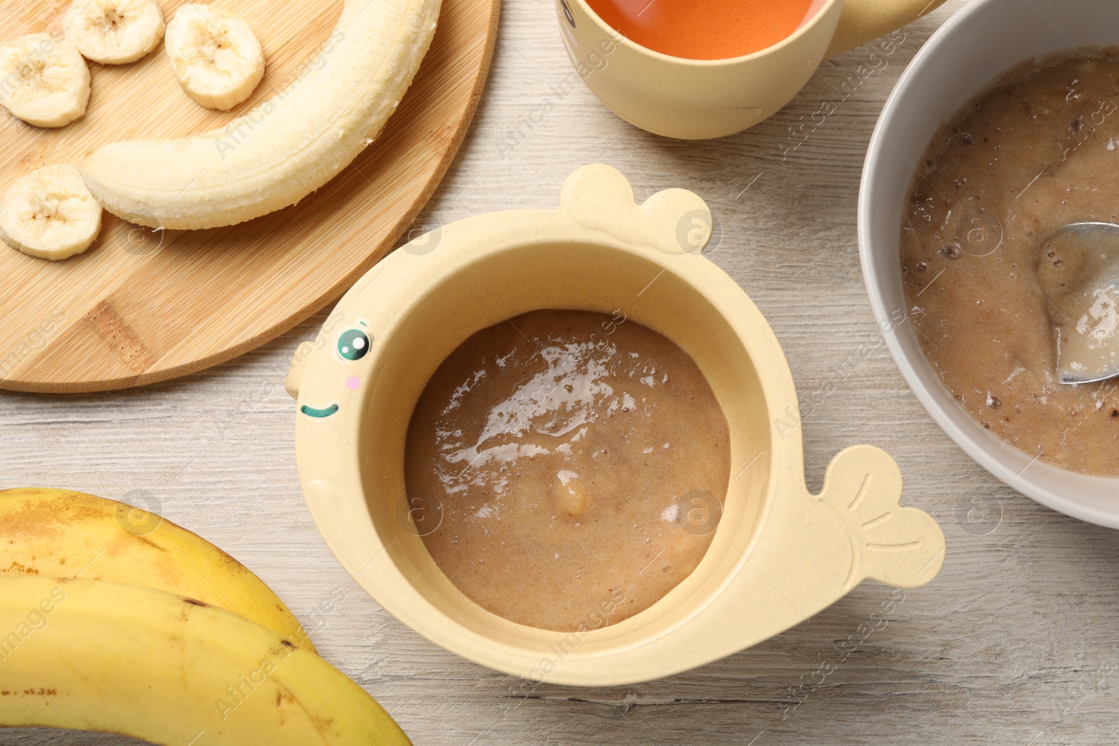 Photo of Baby food. Bowls with banana puree on light wooden table, flat lay