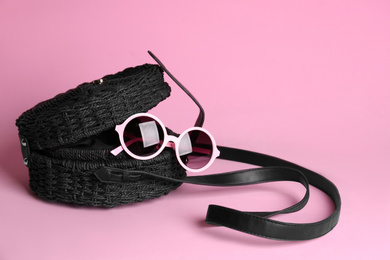 Photo of Stylish woman's bag and sunglasses on light pink background