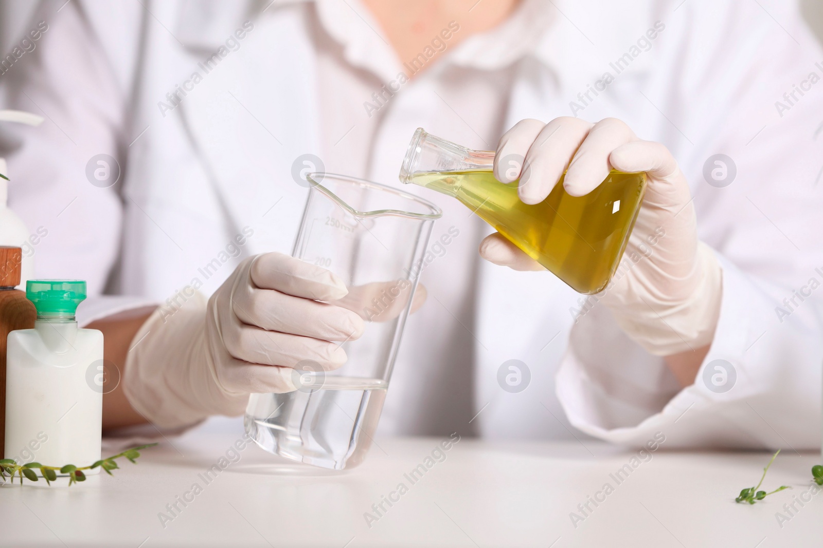 Photo of Dermatologist developing cosmetic product at white table, selective focus