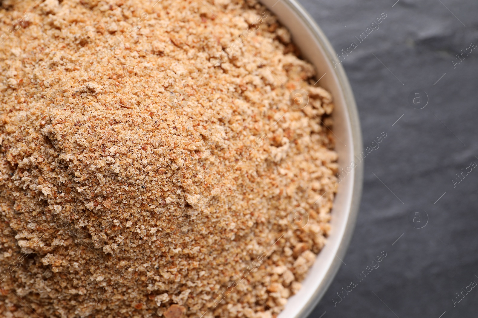 Photo of Fresh breadcrumbs in bowl on black table, top view