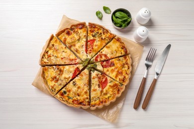 Tasty quiche with tomatoes and cheese served on white wooden table, flat lay
