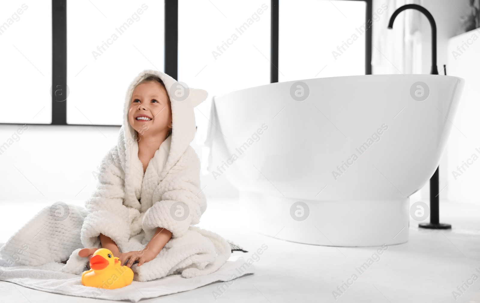 Photo of Cute little girl near tub in bathroom. Space for text