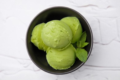 Photo of Tasty matcha ice cream in bowl on white textured table, top view