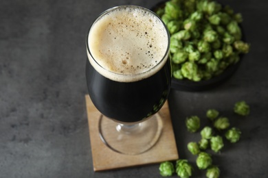 Photo of Composition with tasty beer and fresh green hops on grey table