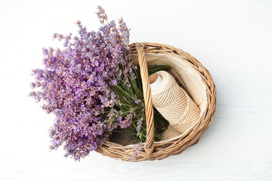Photo of Wicker basket with lavender flowers and rope on light background, top view