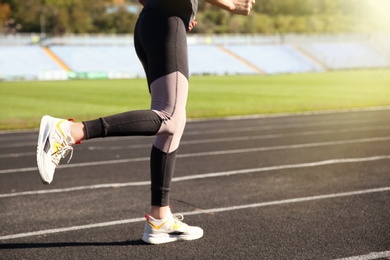 Sporty woman running at stadium on sunny morning