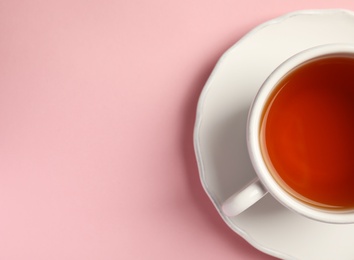 Photo of Cup of delicious tea with saucer on color background, top view