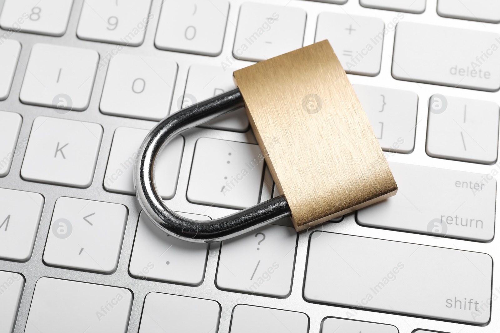 Photo of Cyber security. Metal padlock and keyboard on table, closeup