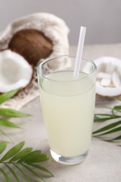 Photo of Glass of coconut water, palm leaves and nuts on light table