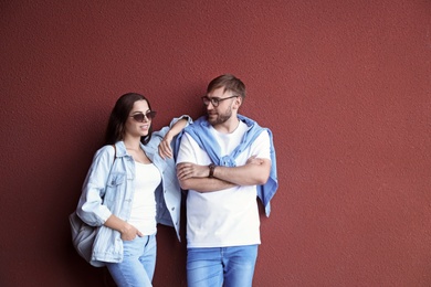 Young hipster couple in stylish jeans posing near color wall