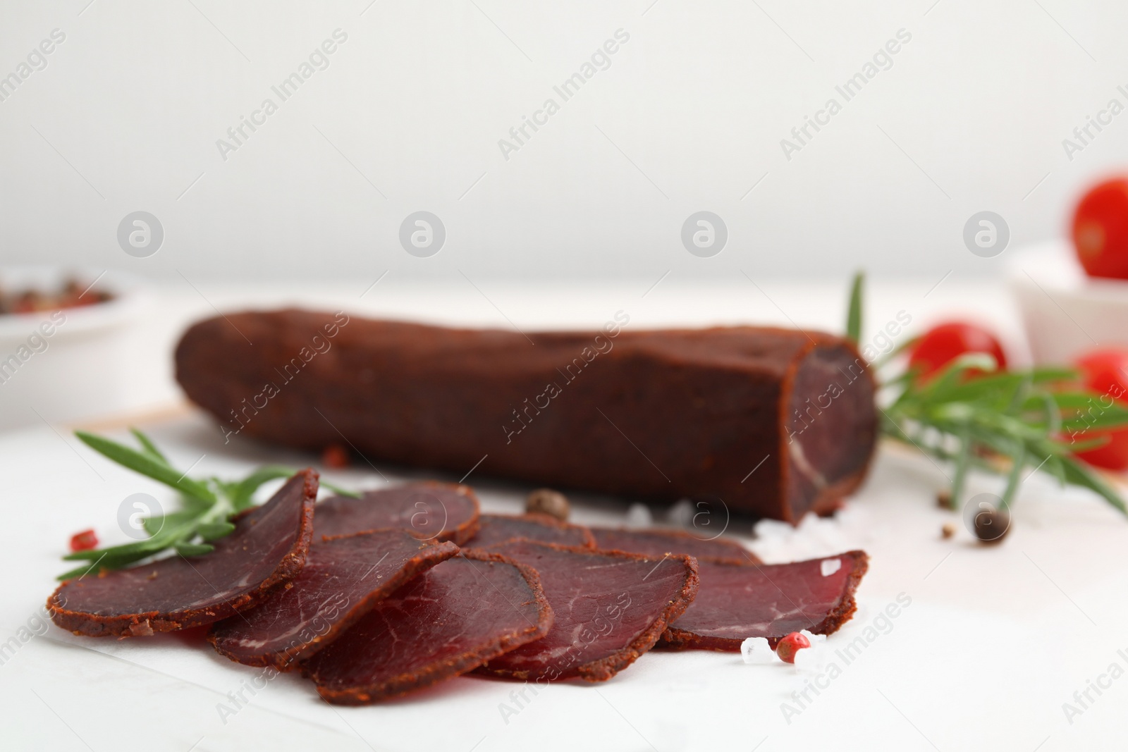 Photo of Delicious dry-cured beef basturma with rosemary and spices on table, closeup