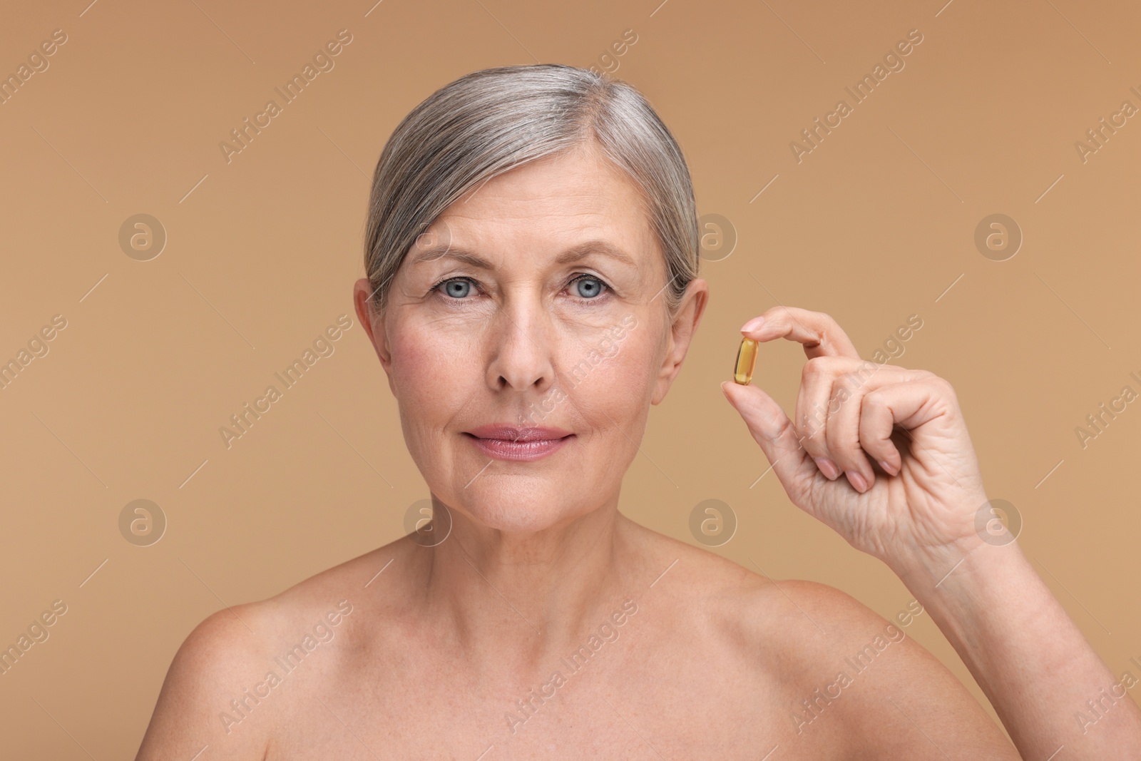 Photo of Beautiful woman with vitamin capsule on beige background