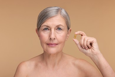 Beautiful woman with vitamin capsule on beige background