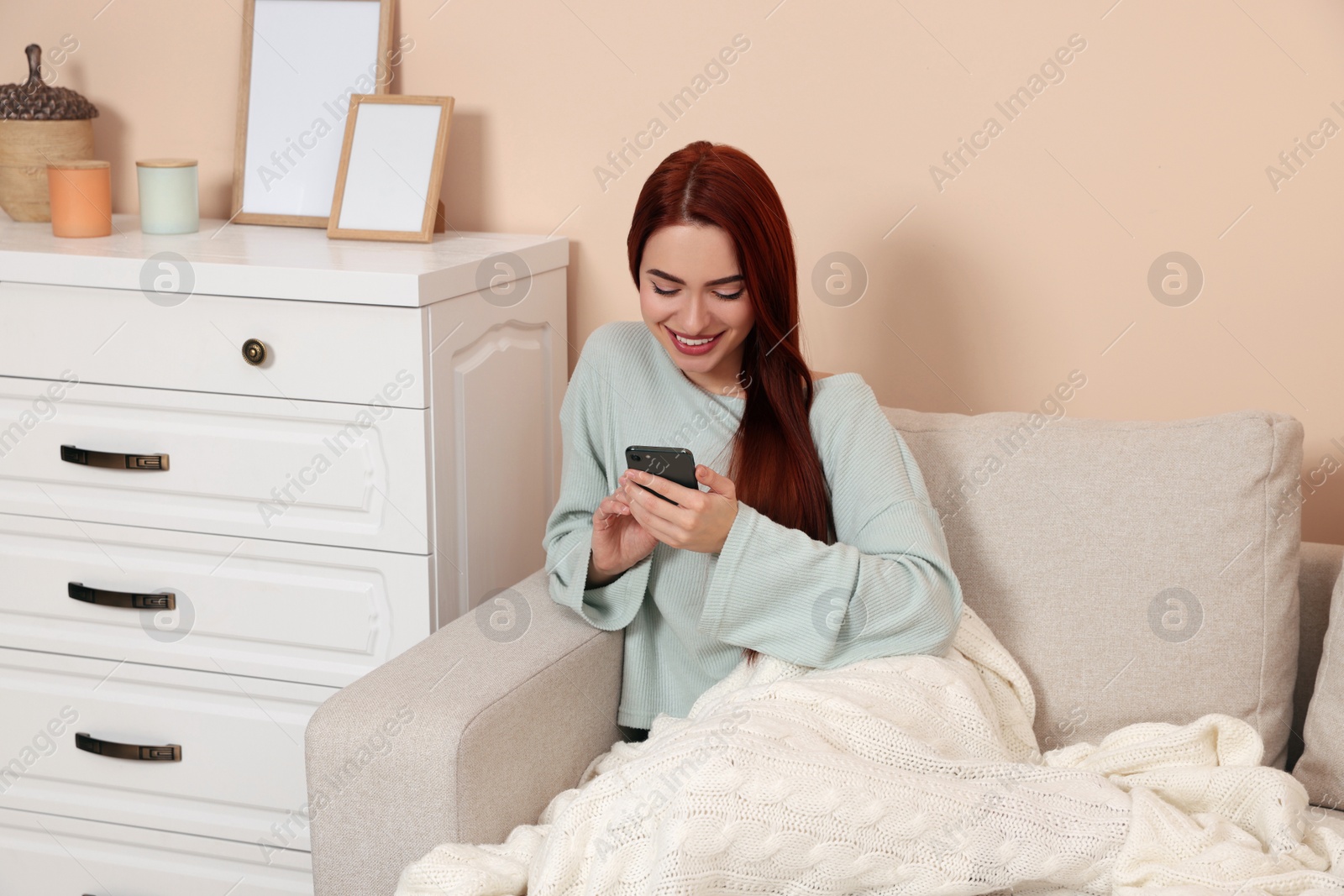 Photo of Happy woman with red dyed hair using smartphone at home