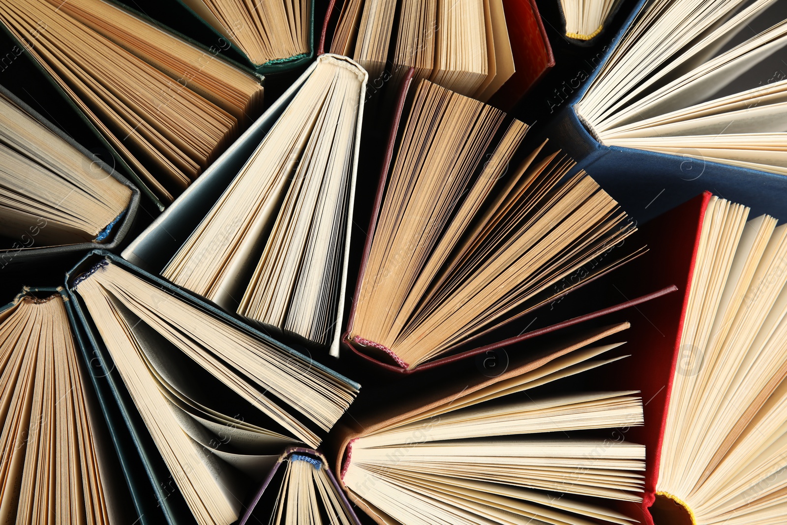 Photo of Many different hardcover books on dark background, top view