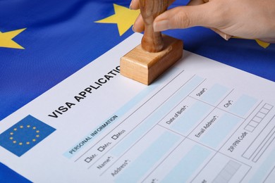 Immigration to European Union. Woman stamping visa application form on flag, closeup
