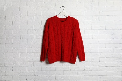 Photo of Hanger with stylish sweater on brick wall