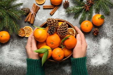 Photo of Woman with fresh tangerines at table, top view. Christmas atmosphere
