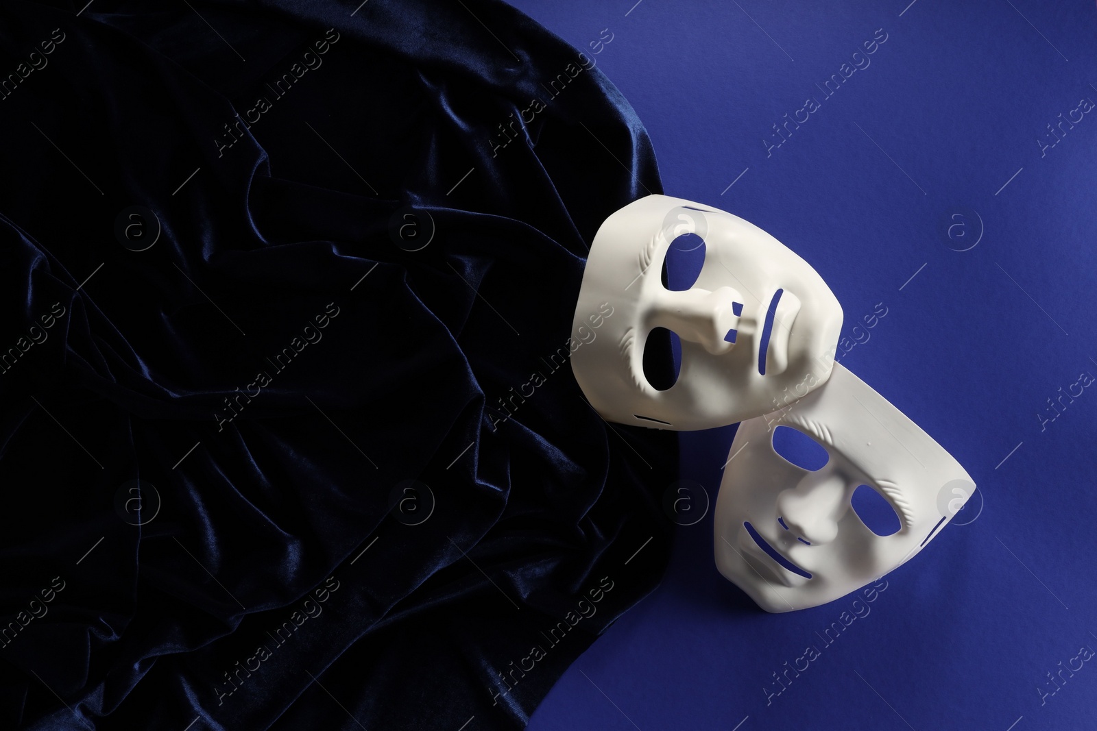 Photo of Theater arts. White masks and fabric on blue background, top view