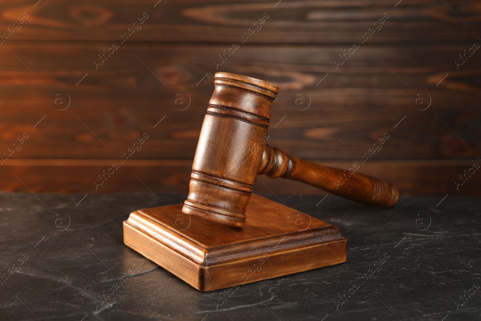 Photo of Wooden gavel and sound block on dark textured table, closeup