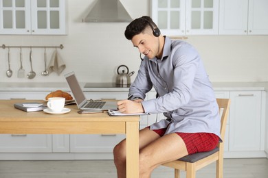 Photo of Businessman in shirt and underwear working at home