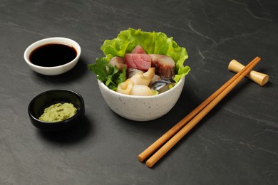 Photo of Delicious mackerel, squid and tuna served with lettuce, parsley, wasabi and soy sauce on grey table. Tasty sashimi dish