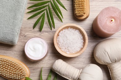 Flat lay composition with spa products and burning candle on light wooden table