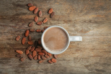 Flat lay composition with hot chocolate drink and cocoa beans on wooden background