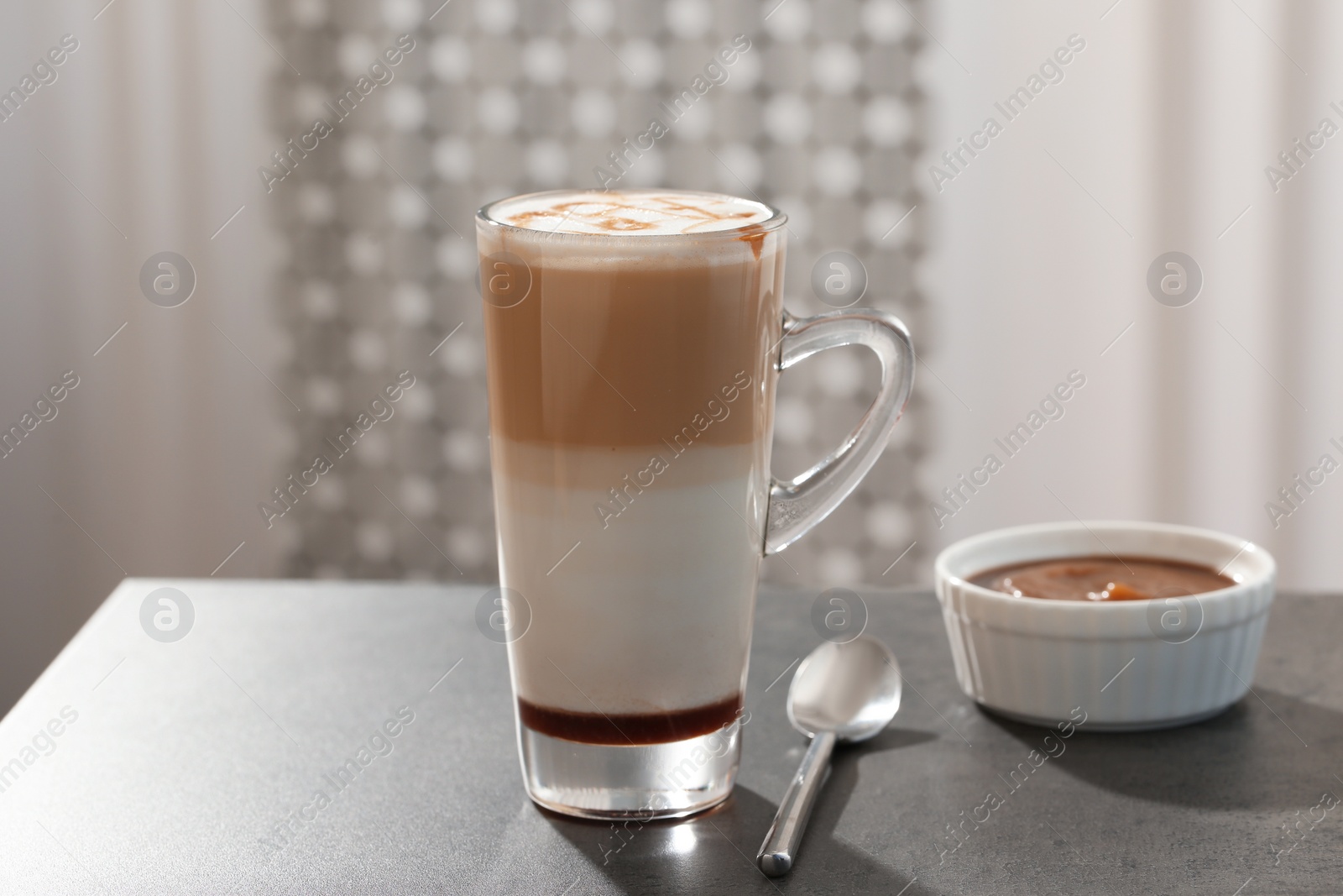 Photo of Glass cup of caramel macchiato and syrup on table