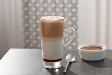 Photo of Glass cup of caramel macchiato and syrup on table