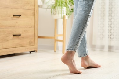 Photo of Woman stepping barefoot in room at home, closeup with space for text. Floor heating