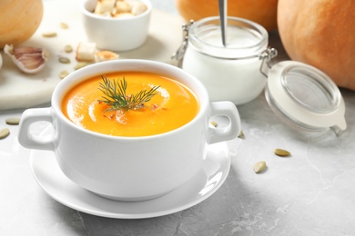 Photo of Delicious pumpkin soup in bowl on marble table