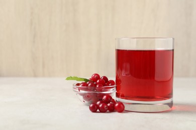 Photo of Tasty refreshing cranberry juice, mint and fresh berries on light table. Space for text