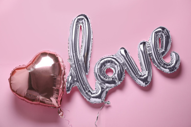 Photo of LOVE word and heart balloons on pink background, flat lay