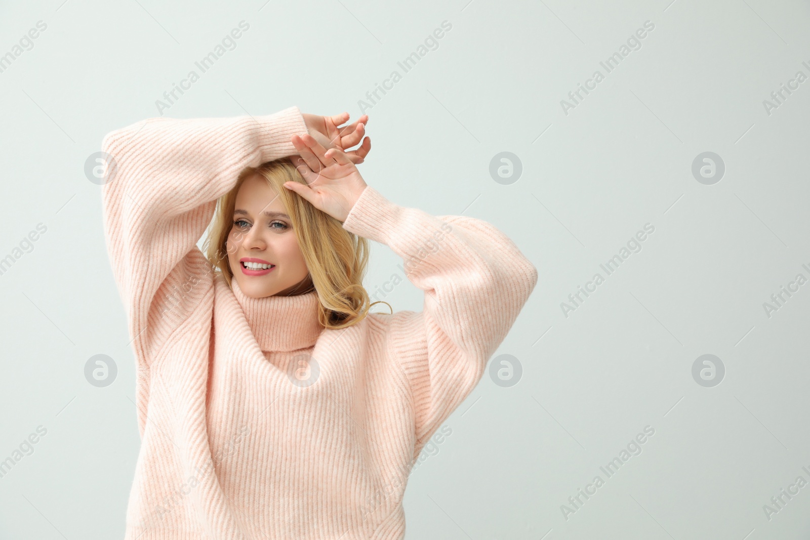 Photo of Beautiful young woman wearing warm pink sweater on white background. Space for text