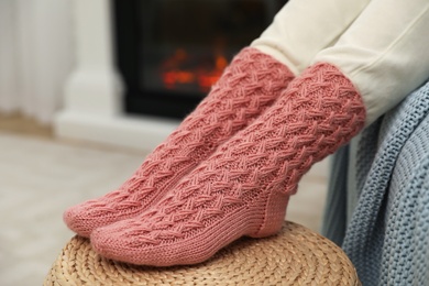 Photo of Woman wearing pink warm socks near fireplace, closeup