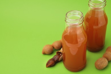 Photo of Tamarind juice and fresh fruits on green background, space for text