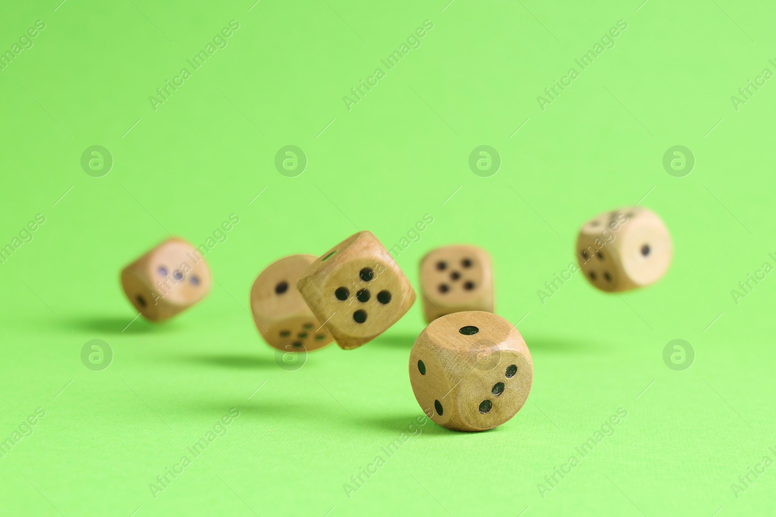 Photo of Many wooden game dices falling on green background. Space for text