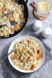 Photo of Delicious scallop pasta with spices served on gray textured table, flat lay