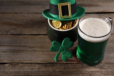 Photo of St. Patrick's day celebration. Green beer, leprechaun hat, pot of gold and decorative clover leaf on wooden table. Space for text