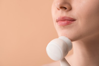 Photo of Washing face. Young woman with cleansing brush on beige background, closeup. Space for text