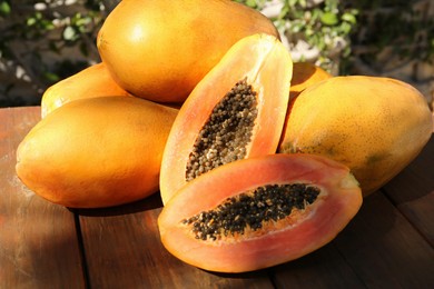 Fresh ripe cut and whole papaya fruits on wooden table outdoors