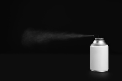 Woman spraying air freshener on black background, closeup