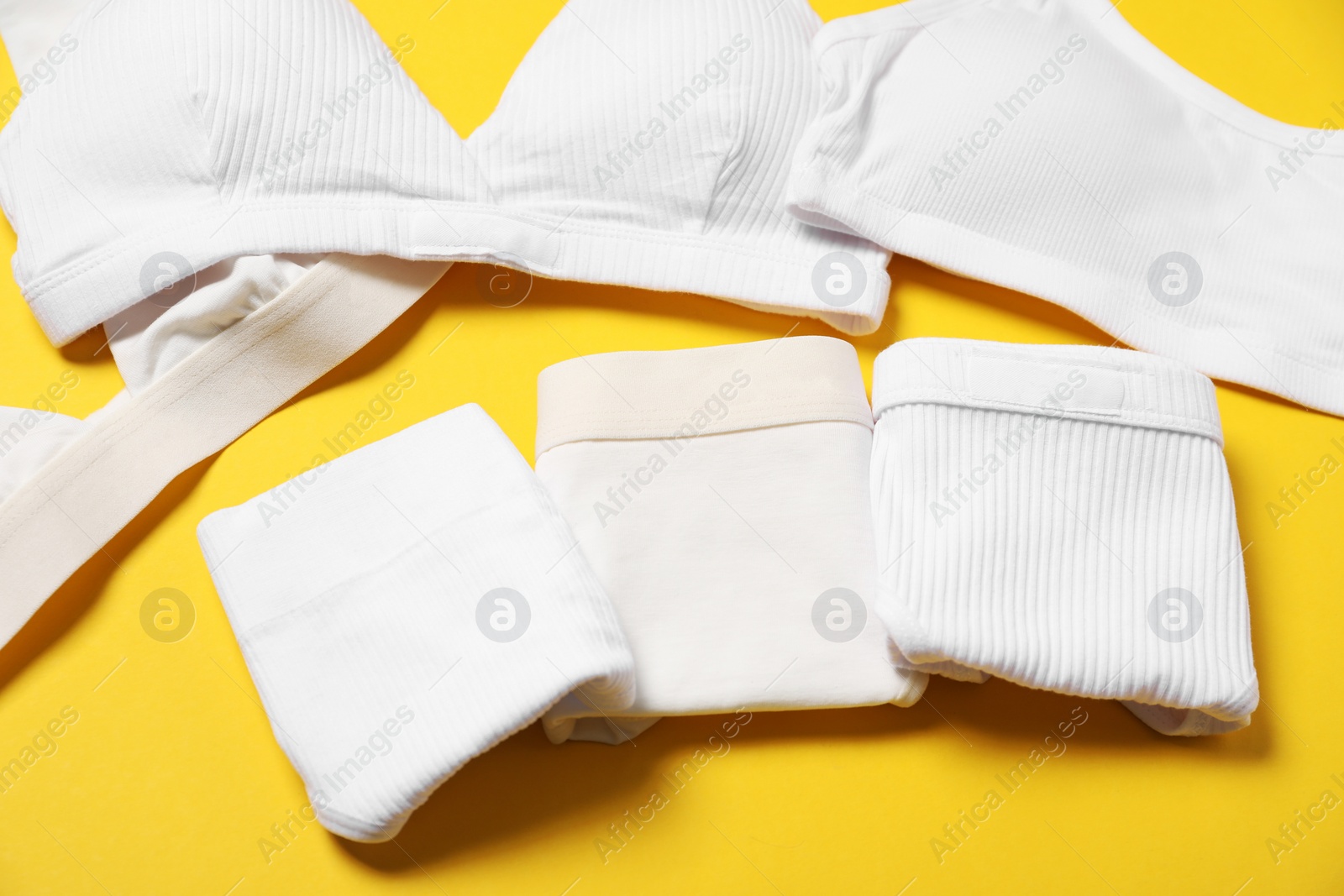 Photo of Stylish folded women's underwear on yellow background