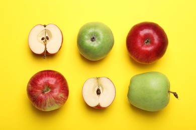 Photo of Whole and cut colorful apples on yellow background, flat lay